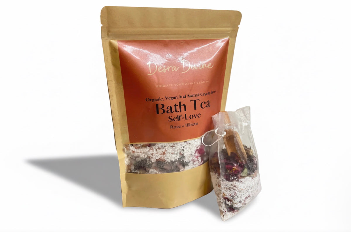 White background displaying Self Love Rose + Hibiscus Bath tea including white bag and wooden spoon containing bath tea in the bag.